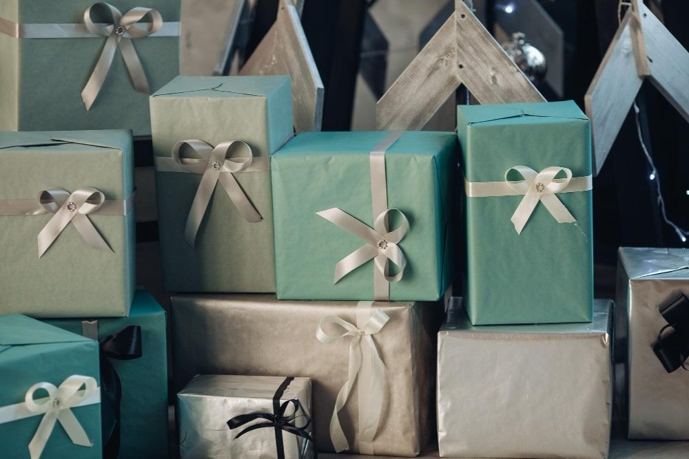 A close-up view of numerous gift-wrapped presents adorned with bows neatly stacked on the floor - Employee Appreciation Gifts