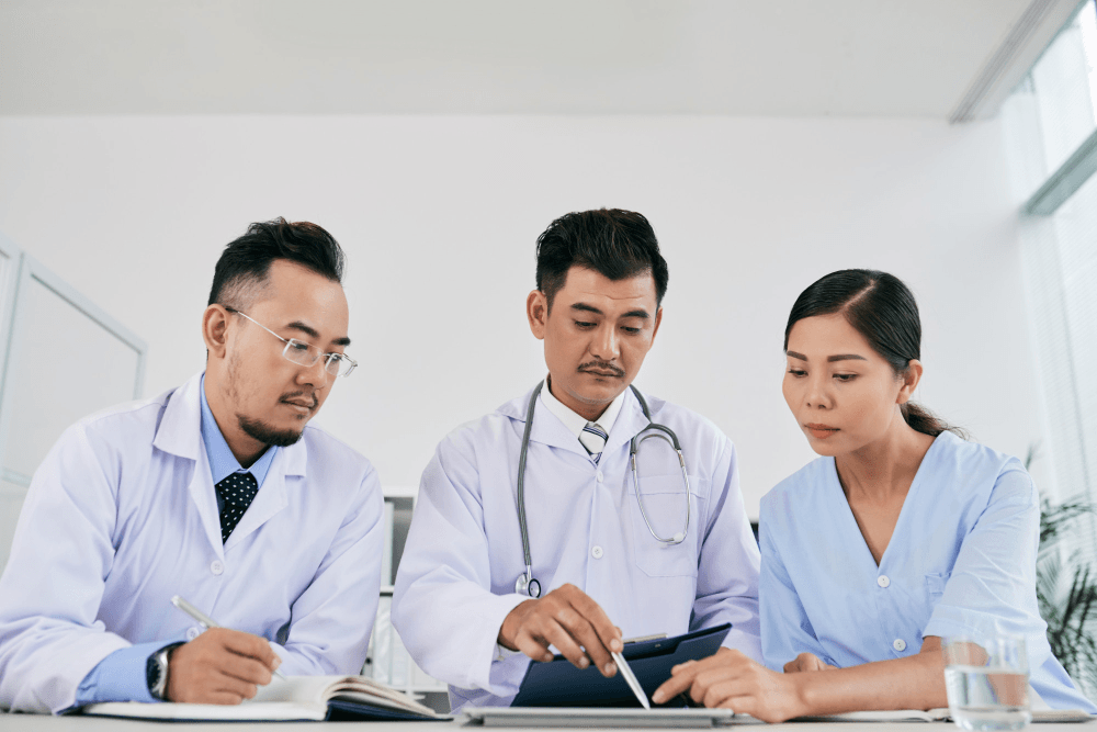 Three male and female medical professionals discussing medical history of patient