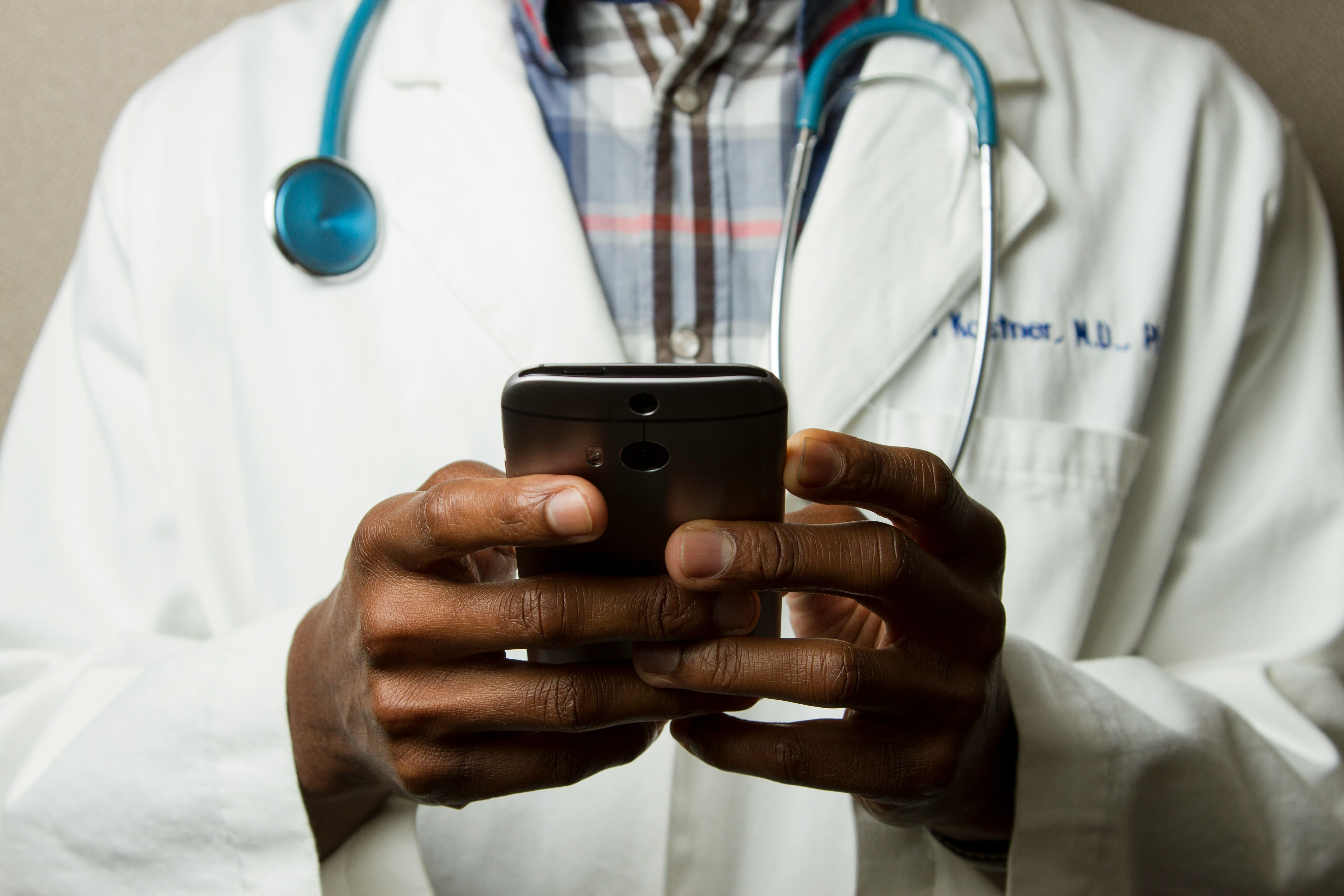 doctor scrolling on his phone - Employee Retention In Healthcare