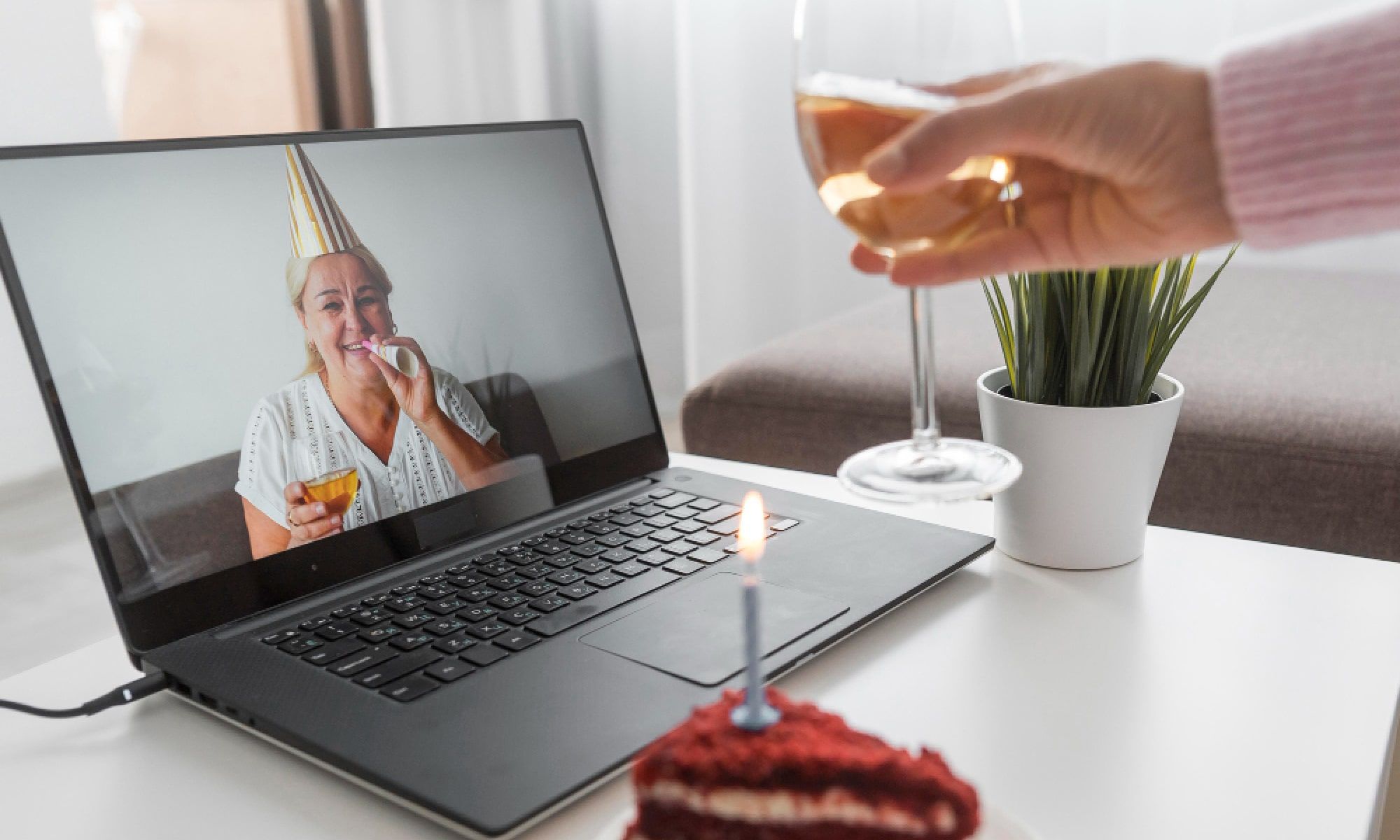 woman celebrating birthday with friends over laptop and cake
